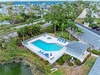 Aerial view of waterfront property featuring swimming pool, hot tub, and tropical landscaping in peaceful residential neighborhood.