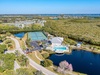 Aerial view of waterfront resort facilities featuring tennis courts, swimming pool, and lakeside clubhouse surrounded by natural Florida landscapes.