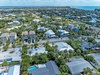 Aerial view of a tropical coastal community with lush palm trees and turquoise waters stretching to the horizon.