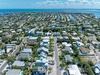 Aerial view of a waterfront community with canals, lush greenery, and proximity to turquoise coastal waters. The property is centrally located in a peaceful residential neighborhood.