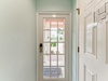 A bright entrance welcomes arrivals, with a classic French door opening to a sunny courtyard and greenery beyond, setting a cheerful tone from the moment you step inside.