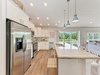 Bright, open kitchen with modern appliances, a large island, and coastal-inspired pendant lighting overlooking lush greenery—your perfect space to gather and create memorable meals.