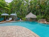 Your private tropical oasis awaits with sparkling pool, shaded loungers, tiki bar, and lush palms—perfect for lazy afternoons and cocktails under the sun.
