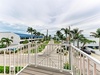 Coastal property overlooking landscaped grounds with palm trees, waterfront access, and nearby community buildings—perfect tropical setting.