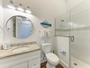 Your bright, coastal-inspired bathroom features a spacious walk-in shower, stylish round mirror, and fresh white subway tiles with calming sea-green accents—perfect for refreshing after a day at the beach.