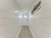 Step into your bright, welcoming hallway with crisp white shiplap walls and warm wood-tone floors that set a cozy, modern farmhouse tone.