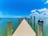 Private dock extending into calm, turquoise waters beneath a vivid blue sky with puffy white clouds, offering waterfront access perfect for boating and water activities.