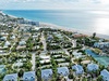Aerial view of beachfront vacation rental community with pristine white sand beach and turquoise waters just steps away.