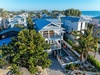 Aerial view of beachfront rental property featuring private pool and tropical landscaping in coastal neighborhood near pristine sandy beach.