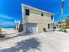 Beachfront retreat with direct access to pristine sand and turquoise waters, featuring garage parking and coastal charm.