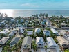 Aerial view of beachside community with tropical homes nestled among palm trees, just steps from pristine coastline.