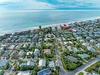 Aerial view of beachfront neighborhood with residential homes just steps from pristine sandy shores and turquoise waters.