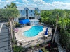 Aerial view of vacation rental property featuring swimming pool area surrounded by palm trees and tropical landscaping.