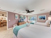Relax in your spacious bedroom with twin beds, ocean-themed artwork, and tropical ceiling fan creating the perfect coastal retreat atmosphere.