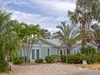 A charming coastal cottage nestled among swaying palms and tropical landscaping, creating a tranquil beachside retreat.