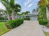 Tropical paradise home surrounded by lush palm trees and manicured gardens with convenient parking.