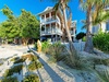 Tropical beachfront property featuring elevated multi-story architecture surrounded by palm trees and native landscaping.