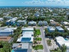 Aerial view of a peaceful coastal neighborhood with tropical landscaping, nearby ocean access, and charming residential streets lined with palm trees and lush greenery.