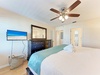 Drift off to sleep in your cozy bedroom featuring a ceiling fan breeze and dreamy beach views on the wall-mounted TV.