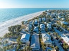 Aerial view showcasing beachfront vacation rental location with pristine white sand beach and turquoise waters nearby.