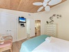 Unwind in your coastal bedroom featuring tropical ceiling fan, wall-mounted TV, and elegant dresser storage.