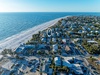 Aerial view of beachfront community with pristine sandy shores and crystal-clear waters just steps from residential properties.
