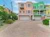 Colorful townhome facades with covered parking and tropical landscaping in a quiet coastal neighborhood. Your arrival is marked by a spacious paver driveway.