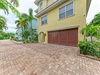 The property features a charming Mediterranean-style exterior with warm stucco tones and tropical landscaping, complete with convenient paver driveway parking and a multi-car garage.