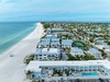 Stunning aerial view of the beachfront property showcasing its prime location steps from pristine white sand and turquoise waters.