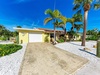 Tropical paradise awaits at this charming yellow beach home, surrounded by swaying palms and lush landscaping under brilliant blue skies.