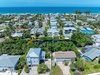 A beachfront neighborhood featuring vacation homes with private pools, lush tropical landscaping, and direct access to pristine white sand beaches and crystal-clear turquoise waters along the coast.