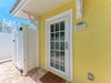 A cheerful yellow facade with decorative trim marks the entrance to this coastal vacation home, framed by swaying palms and tropical breezes.