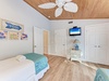 Drift off to sleep in your coastal-themed bedroom with twin beds, ceiling fan, and cheerful beach decor creating the perfect seaside retreat.