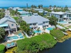 Aerial view of this coastal vacation home featuring private pools, lush tropical landscaping, and waterfront access, set in a serene seaside neighborhood near the ocean.