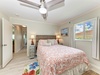 Unwind in this bright, coastal-inspired bedroom where soft linens and a gentle ceiling fan invite restful sleep. Large windows frame peaceful outdoor views, completing your serene retreat.