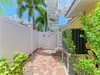 The property entrance features a private pathway with tropical landscaping, a spiral staircase, and modern climate control—a welcoming arrival to your coastal getaway.