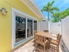 The sunny yellow exterior opens to your private patio, where palm trees sway overhead and outdoor dining awaits under bright Florida skies—perfect for morning coffee or evening meals.