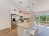 A bright, coastal-inspired kitchen opens to a balcony overlooking lush greenery, perfect for gathering over meals and enjoying the peaceful views beyond your windows.