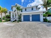 Modern coastal home featuring pristine white architecture, tropical landscaping, and convenient two-car garage parking in a serene residential setting.