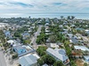 Aerial view of a charming coastal neighborhood with tree-lined streets leading to pristine beaches and sparkling ocean waters.