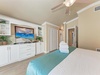 Unwind in your coastal bedroom with custom built-ins, ceiling fan, and beach-themed TV setup for ultimate relaxation.