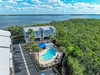 Waterfront vacation rental complex featuring pool and tropical landscaping, surrounded by lush natural preserve near the coast.