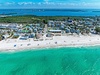 Aerial view of a stunning beachfront community with pristine white sand and crystal-clear turquoise waters.