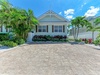 A charming cottage-style property nestled among lush tropical palms and vibrant landscaping, welcoming guests with coastal elegance and sunny Florida charm.