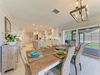 Gather around this inviting dining table, perfectly set for memorable meals together. Soft natural light streams in from the private screened lanai, while the open kitchen layout keeps conversation flowing.