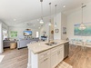 Your open-concept living space features a fully equipped kitchen island with granite counters, a cozy living room, and a bright dining area—all bathed in natural light and coastal charm.