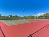 Perfect your serve on this pristine tennis court surrounded by lush tropical greenery under brilliant blue skies.