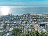 Aerial view of a charming beachside neighborhood with your vacation rental highlighted, just steps from pristine sandy shores and crystal-clear waters.