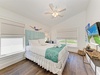 Sink into crisp white linens and coastal charm, where your personal ceiling fan keeps you comfortable and cheerful beach art sets a serene, relaxing tone for your stay.