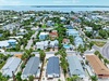 Aerial view of a lush coastal neighborhood featuring palm-lined streets, colorful rooftops, and sparkling waterfront views. This tropical residential area is just moments from the beach.